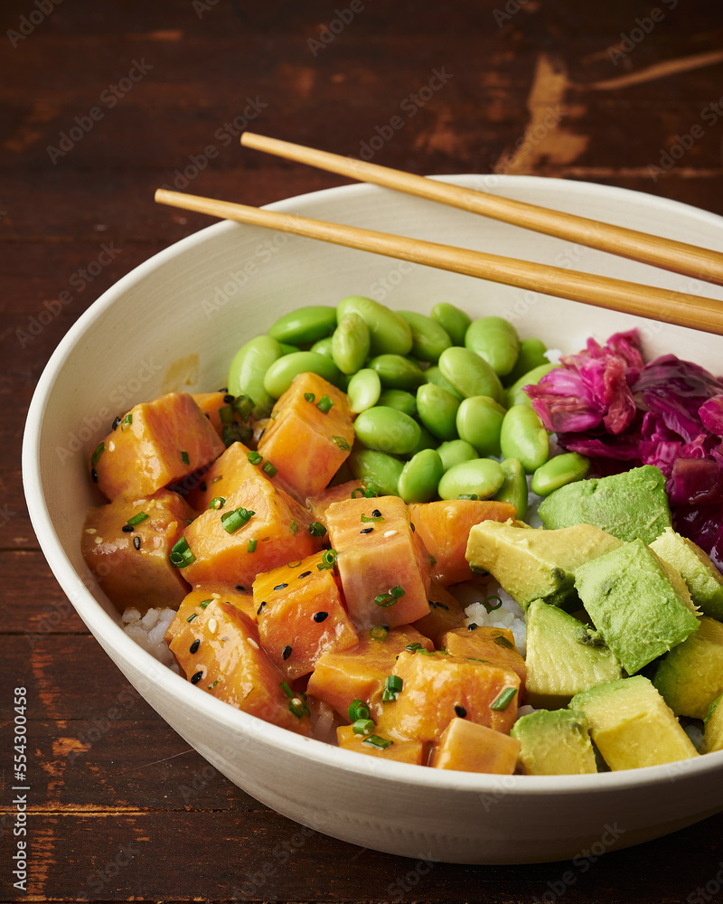 A vibrant poke bowl with cubed salmon, avocado, edamame, and pickled red cabbage on rice, perfect for culinary stock imagery. A vibrant poke bowl with cubed salmon, avocado, edamame, and pickled red cabbage on rice, perfect for culinary stock imagery.