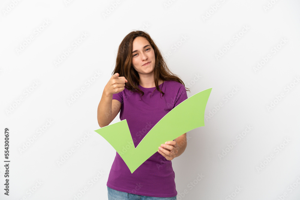 Young caucasian woman isolated on white background holding a check icon and pointing to the front Young caucasian woman isolated on white background holding a check icon and pointing to the front