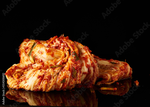 A vibrant pile of kimchi, with a glossy finish, set against a dark backdrop, perfect for a culinary stock photo highlighting Korean cuisine.