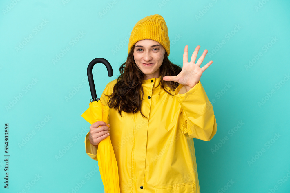 Young caucasian man holding an umbrella isolated on blue background counting five with fingers Young caucasian man holding an umbrella isolated on blue background counting five with fingers