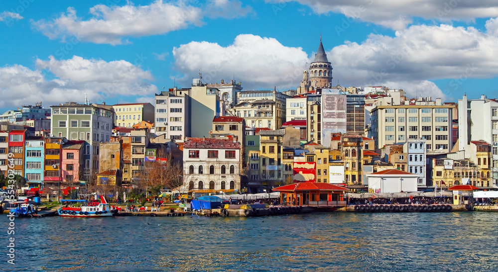 Obraz premium Istanbul, Turkey - February 24. 2017: Panorama city skyline view on historic peninsula Galata district (Karaköy), Sarayburnu tower across the bosphorus Golden Horn estuary waterway in springtime