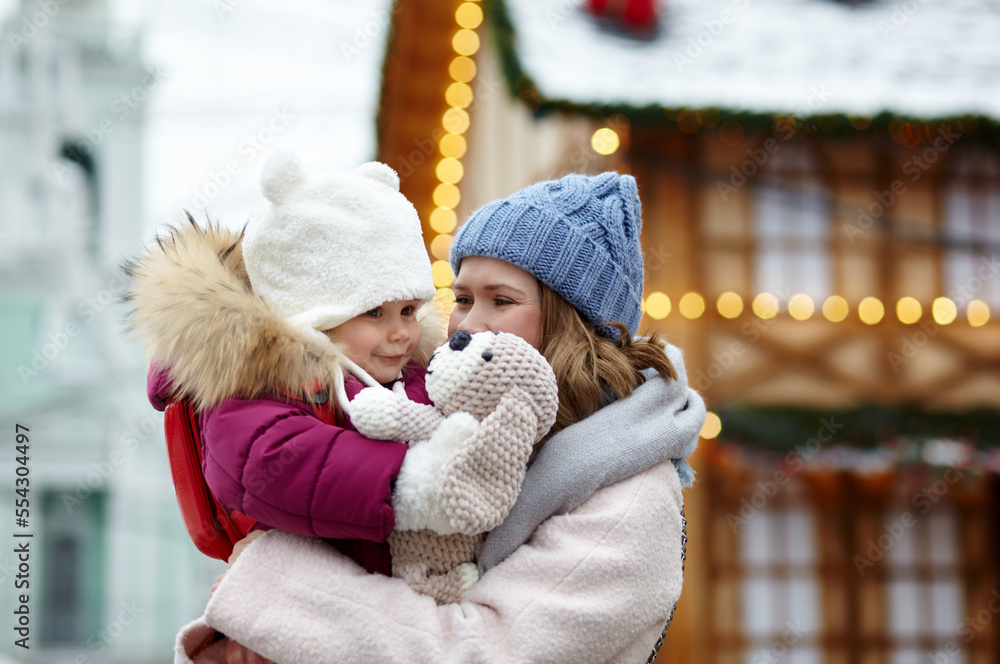 Mother and daughter are walking around the city on Christmas and New Year holidays. Parent and little child having fun outdoors Mother and daughter are walking around the city on Christmas and New Year holidays. Parent and little child having fun outdoors