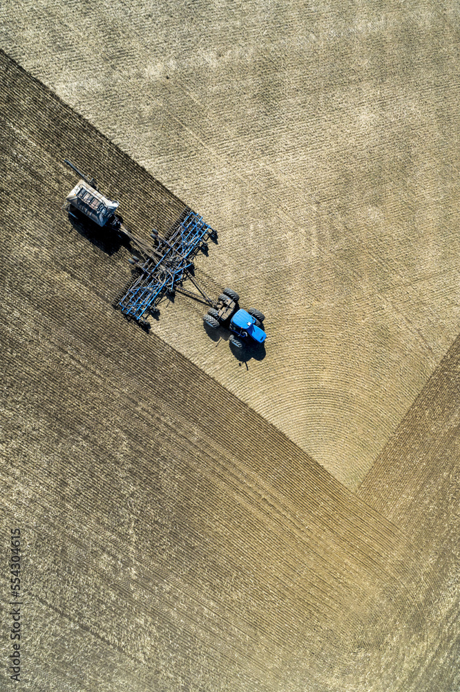Aerial view of a tractor pulling an air seeder, seeding a field; Acme, Alberta, Canada Aerial view of a tractor pulling an air seeder, seeding a field; Acme, Alberta, Canada