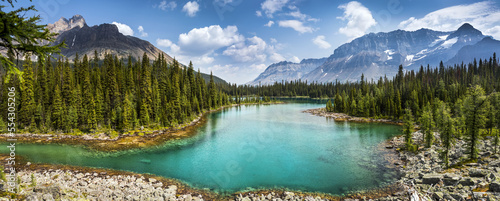 Colourful alpine lake with mountains, blue sky and clouds in the background; British Columbia, Canada