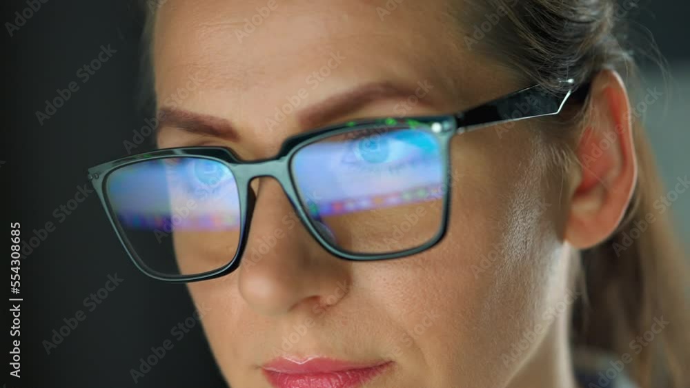 Woman in glasses looking on the monitor and working with charts at night Woman in glasses looking on the monitor and working with charts at night
