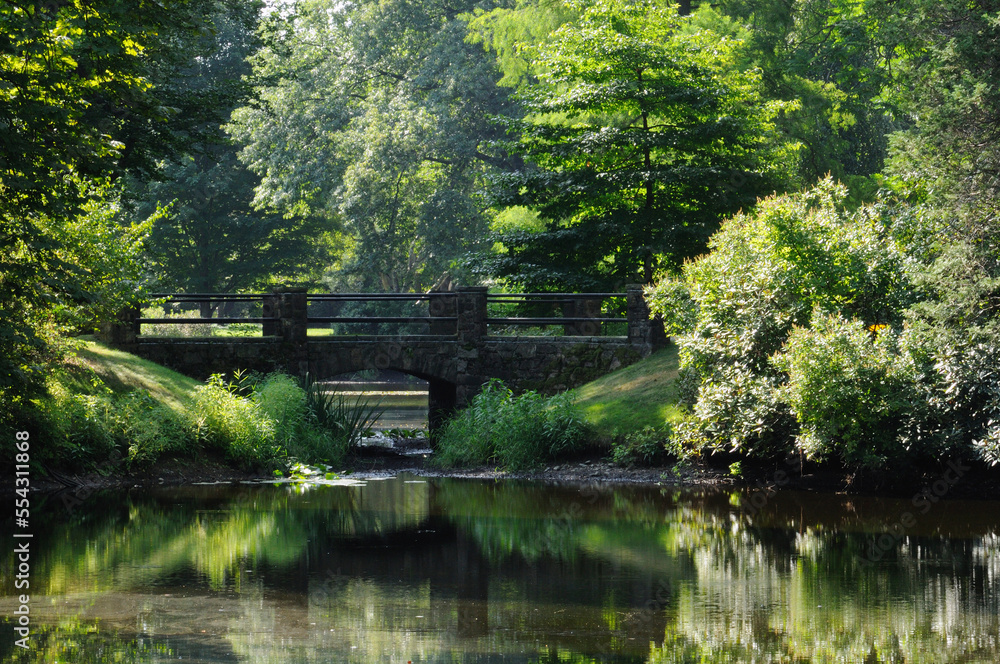 Scenic view of a pond with a stone footbridge.; Cambridge, Massachusetts. Scenic view of a pond with a stone footbridge.; Cambridge, Massachusetts.