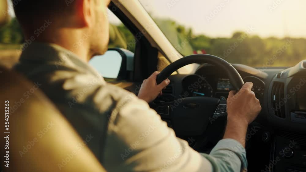 Man drives a car along the road, the setting sun shines in the windshield. Man drives a car along the road, the setting sun shines in the windshield.