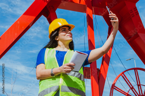 latin young caucasian female engineer taking a selfie with her phone during work photo