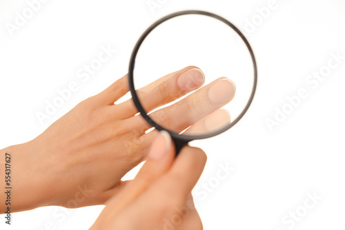 Close up shot of fresh done manicure nails through a magnifying glass. Over white background.