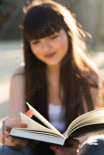 Detail shot of a book with black cover, read for a young girl in a park