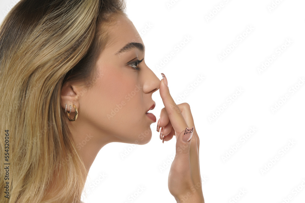 young woman touches her nose with her finger on a white background young woman touches her nose with her finger on a white background