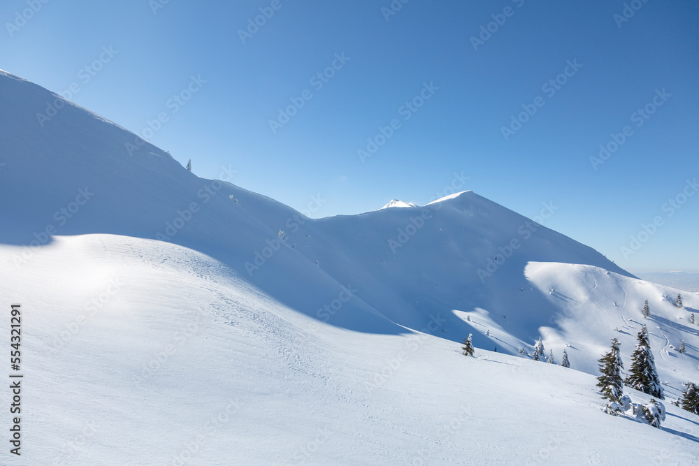 Winter in mountains. Alpine mountains landscape with white snow and blue sky.