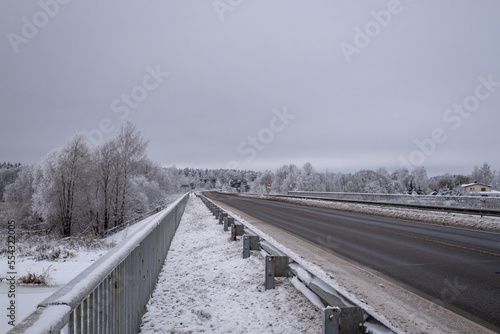 clean wet asphalt road in wintertime. Dirty snow on road sides. Long far perspective. Latvia landscape near Jelgava town. Bypass road 