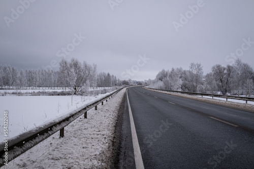 clean wet asphalt road in wintertime. Dirty snow on road sides. Long far perspective. Latvia landscape near Jelgava town. Bypass road  © Neils