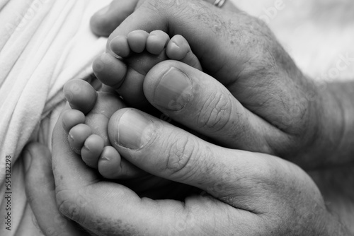 Children's foot in the hands of mother, father, parents. Feet of a tiny newborn.