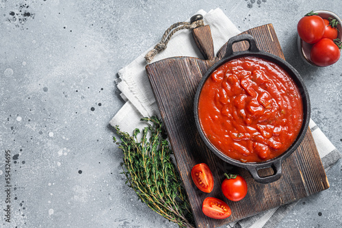 Homemade red tomato sauce with basil in pan. Gray background. Top view. Copy space photo