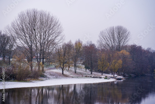 Snowy landscape at lake, winter trees on the shore