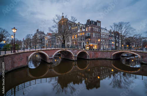 Fototapeta Naklejka Na Ścianę i Meble -  Reflection of historic canal houses and arched bridge over the Prinengracht canal in Amsterdam at dusk