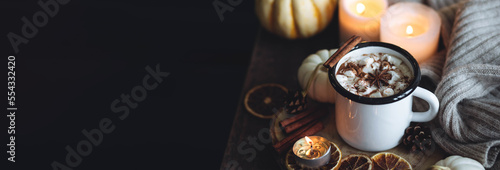 Autumn cozy home composition with hot chocolate with marshmallow and candles. Aromatherapy on a grey fall morning, atmosphere of cosiness and relax. Wooden background close up banner copy space