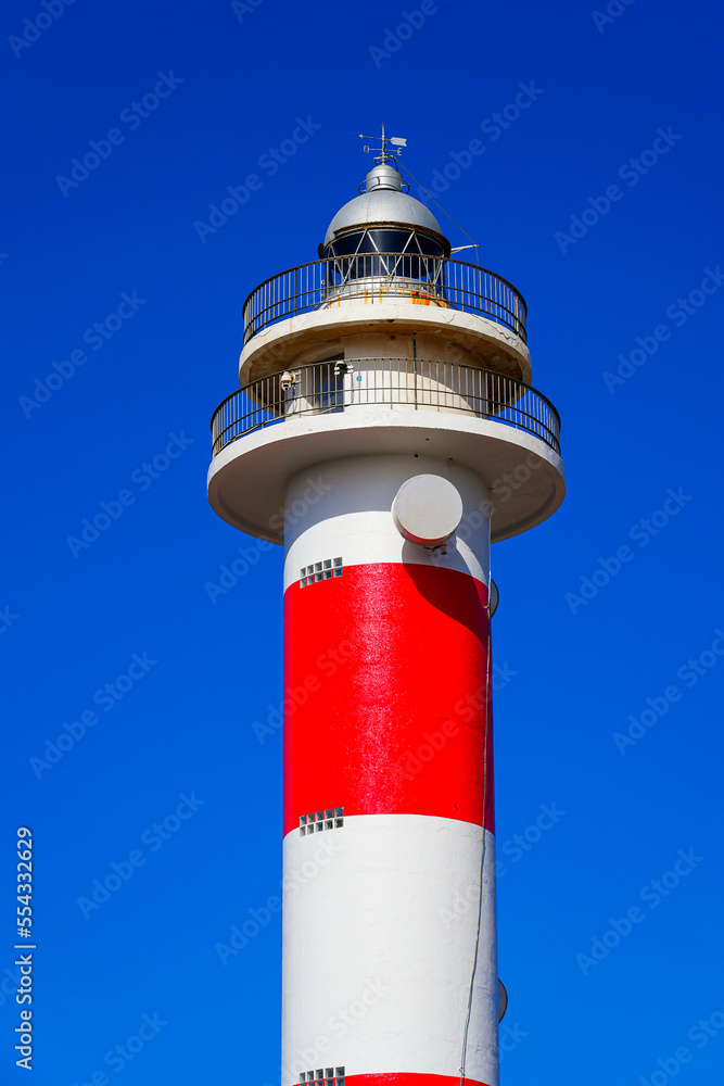 Red and white striped tower with a 2-stories observation deck and a domed lantern of the lighthouse of El Toston on the north coast of Fuerteventura in the Canary Islands, Spain