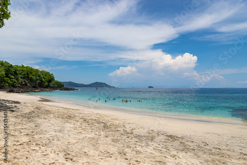 Fototapeta Naklejka Na Ścianę i Meble -  BALI, INDONESIA - NOVEMBER 6, 2022: Bias Tugel beach at the south of Bali island. Many tourists swimming in blue ocean water. White sand and rock shore.