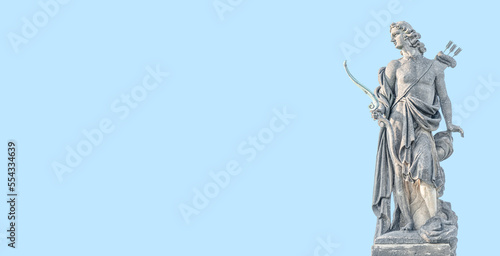 Old statue of Renaissance Era Roman man hunter, archer with a bow and arrows, Potsdam, Germany, at solid blue sky background and copy space