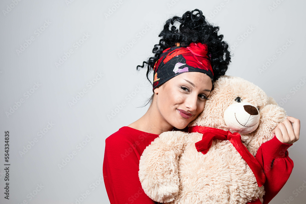 Fototapeta premium Beautiful curly young girl with bandana hairstyle holding teddy bear