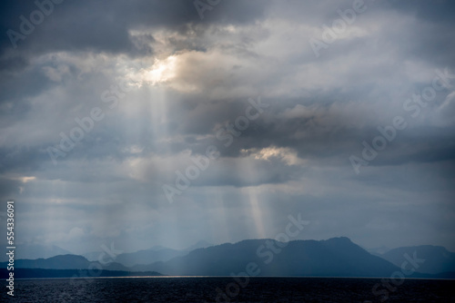 Sunlight breaking through rain clouds in Chatham Strait, in Southeast Alaska; Alaska, United States of America photo