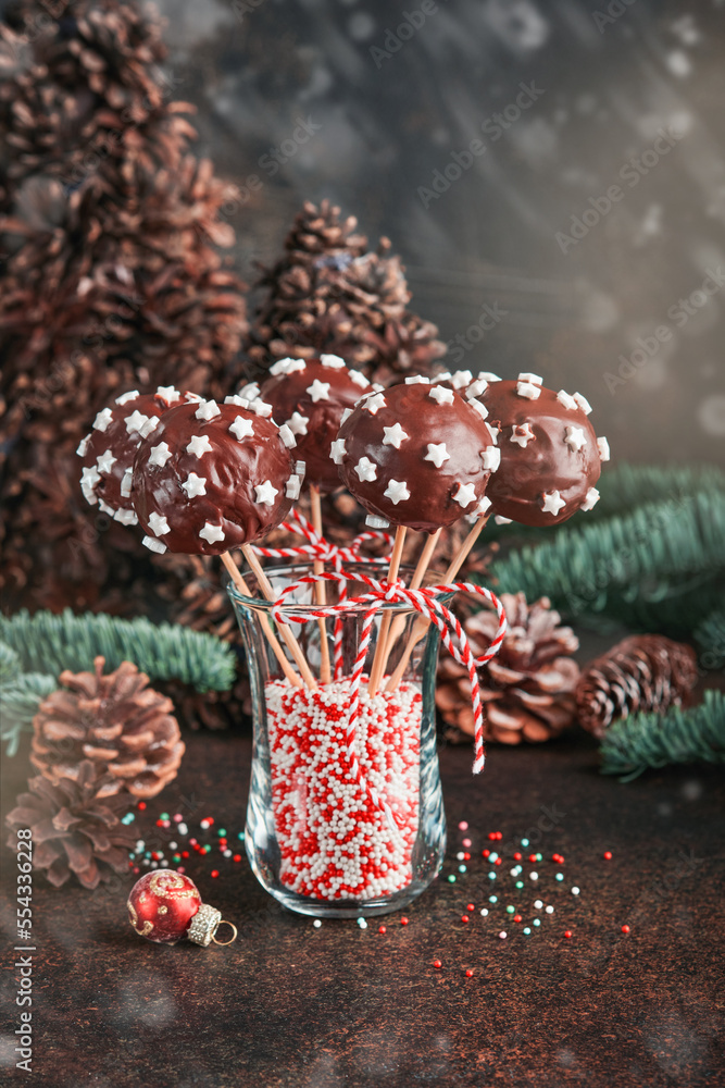 Marry Christmas sweet cake pops. Christmas dessert round brownie cake pops with stars topping on dark green background. Christmas food dessert concept and scene wide screen holiday border. Top view
