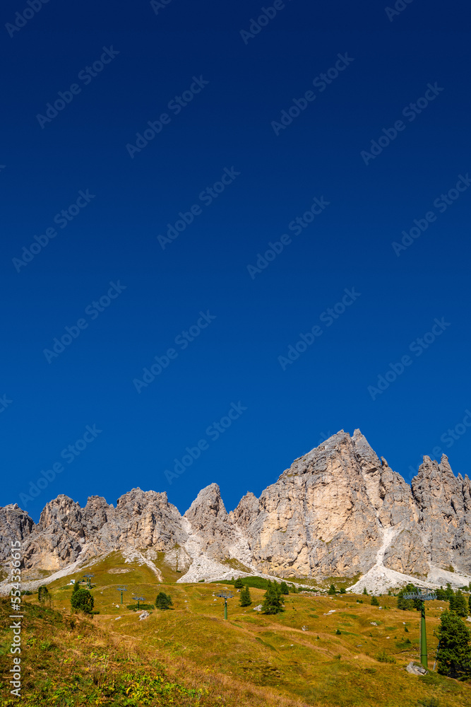 Cover page with magical granite Dolomite peaks and alpine forests of Pizes da Cir, Passo Gardena, Colfosco at blue sky and sunny day, South Tyrol, Alps, Italy, with copy space and gradient background
