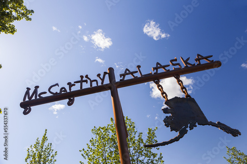 Low angle view of a sign for McCarthy, Alaska against a blue sky; McCarthy, Alaska, United States of America photo