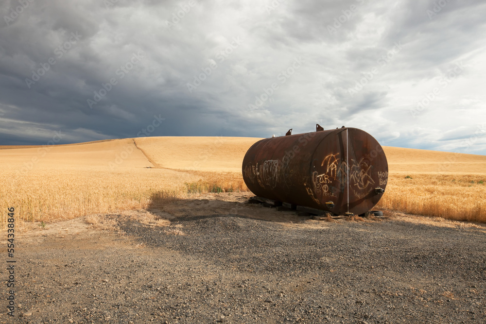 A rusted cylindrical tank covered in graffiti in the middle of a wheat field.; Kennewick, Washington A rusted cylindrical tank covered in graffiti in the middle of a wheat field.; Kennewick, Washington