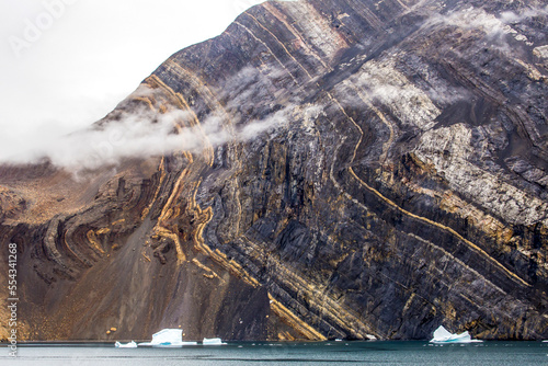 Seaside mountain with visible sedimentary layers. photo