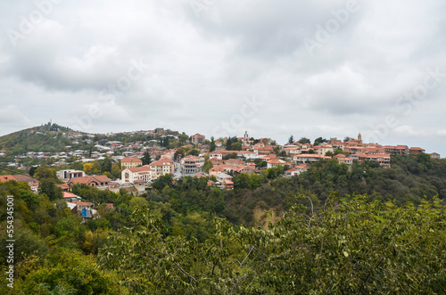 View of the picturesque buildings of the city of Sighnaghi on the hill with colored autumn leaves and trees at foggy day. Georgia