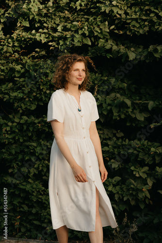 Obraz na płótnie A woman with curly hair is posing in the garden in the evening. w salonie