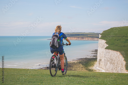 A woman riding bicycle on Seven Sisters chalk cliffs, Eastbourne, East Sussex, England, UK