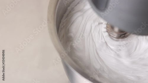 Kitchen mixer is beating the eggs white egg whites into a thick white foam. whisks whipped egg whites and sugar in the metal bowl. Whip the egg white: cook at home, make a cake, desserts, meringue photo