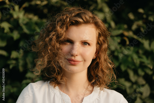 Obraz na płótnie A woman with curly hair is posing in the park at the sunset. w salonie
