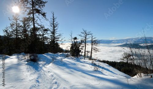 View from a peak overlooking a mist filled valley on a bright winter day.