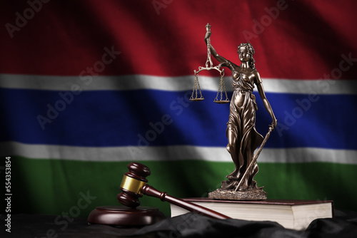 Gambia flag with statue of lady justice, constitution and judge hammer on black drapery. Concept of judgement and punishment photo