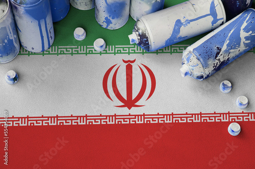 Iran flag and few used aerosol spray cans for graffiti painting. Street art culture concept, vandalism problems photo