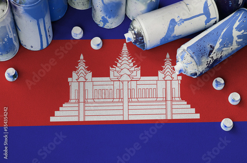 Cambodia flag and few used aerosol spray cans for graffiti painting. Street art culture concept, vandalism problems photo