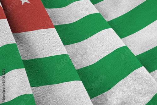 Abkhazia flag with big folds waving close up under the studio light indoors. The official symbols and colors in fabric banner photo