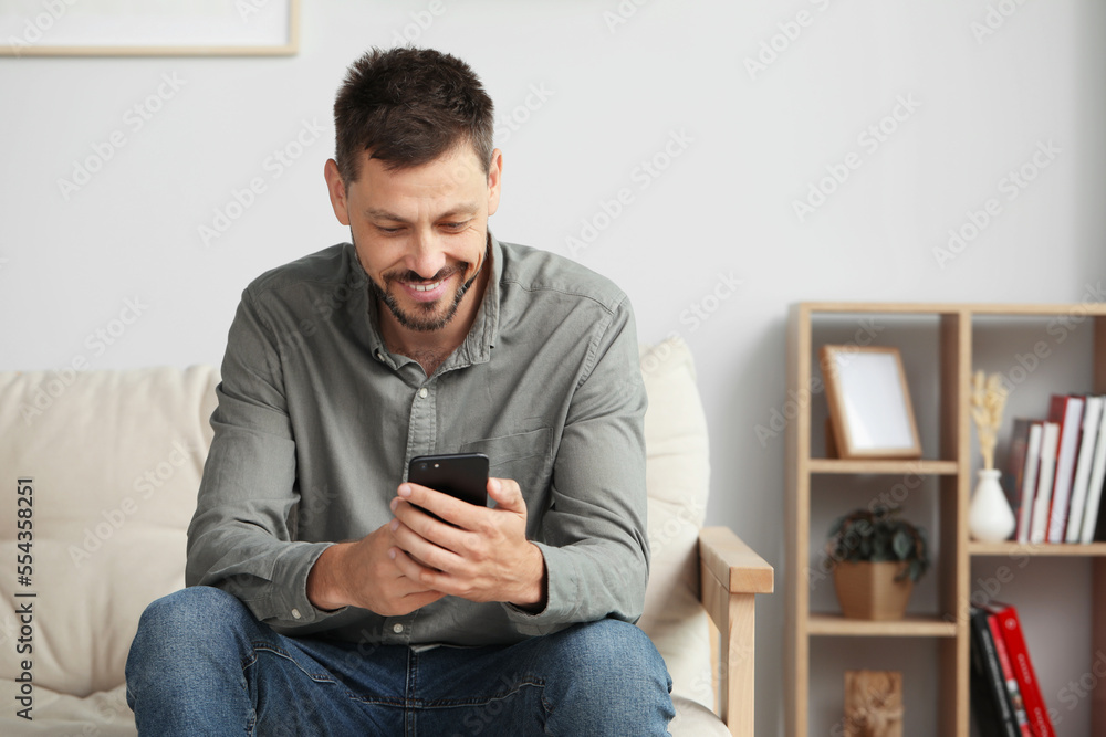 Happy handsome man using smartphone at home
