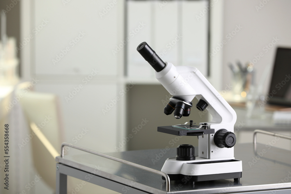Modern medical microscope on metal table in laboratory, space for text Modern medical microscope on metal table in laboratory, space for text