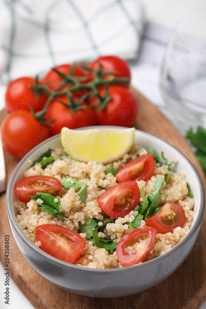 Delicious quinoa salad with tomatoes, parsley and lime served on white wooden table Delicious quinoa salad with tomatoes, parsley and lime served on white wooden table