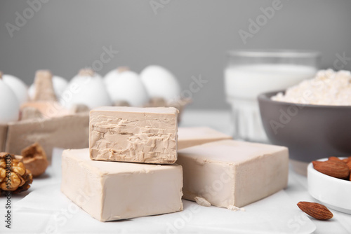 Blocks of compressed yeast and ingredients for dough on white table, closeup