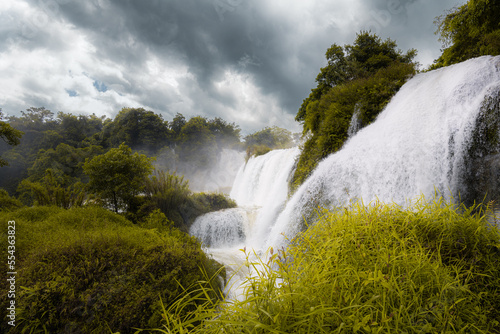 Green leaves and dark dramatic sky around Detian Waterfall at Cao Bang  Vietnam. Ban Gioc Waterfall