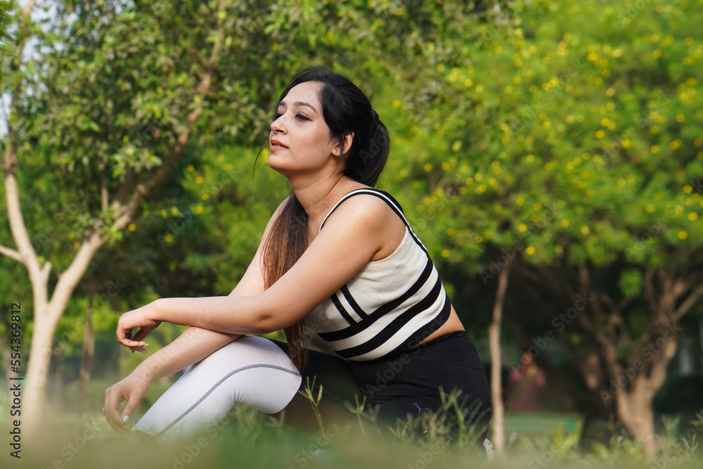 Side view of Indian young woman while relaxing in the park Side view of Indian young woman while relaxing in the park