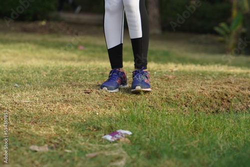 Sports shoes on the green park of a young sports woman